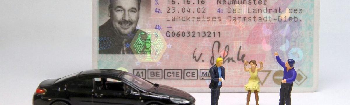 Foto mit einem Führerschein, einem Auto und drei Plastikfiguren