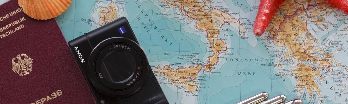 Foto von einem Reisepass, Fofoapparat un Stiften auf einer Weltkarte